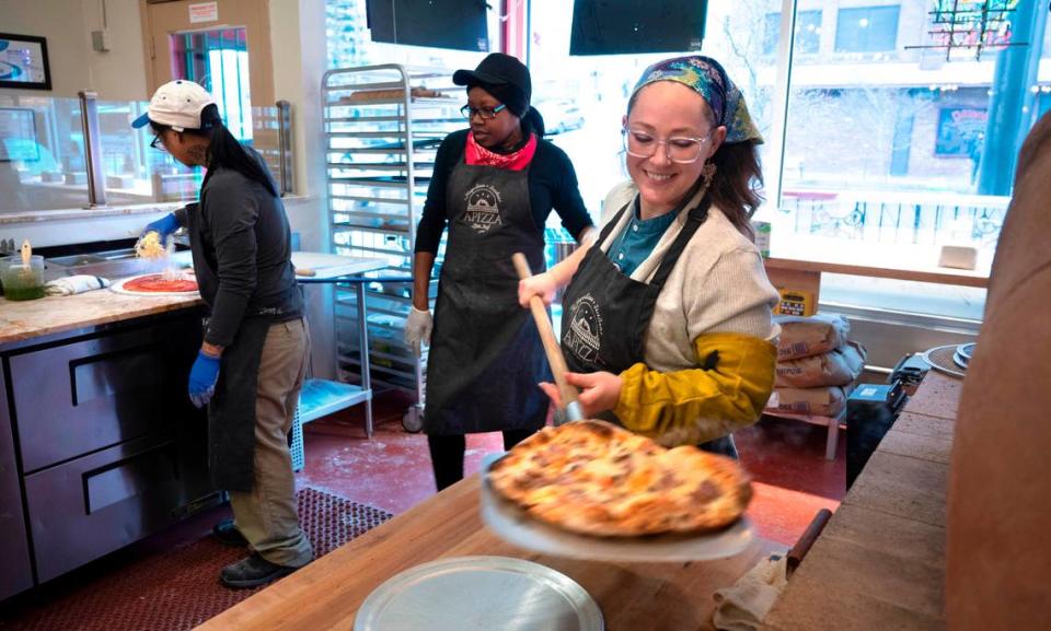 General manager Cassi Curtis pulls an off-menu pizza (the Napoli with salami, artichoke hearts, roasted red peppers and pepperonicinis) from the gas-fired clay oven at APIZZA Little Italy in downtown Tacoma, Washington, on Thursday, March 9, 2023.