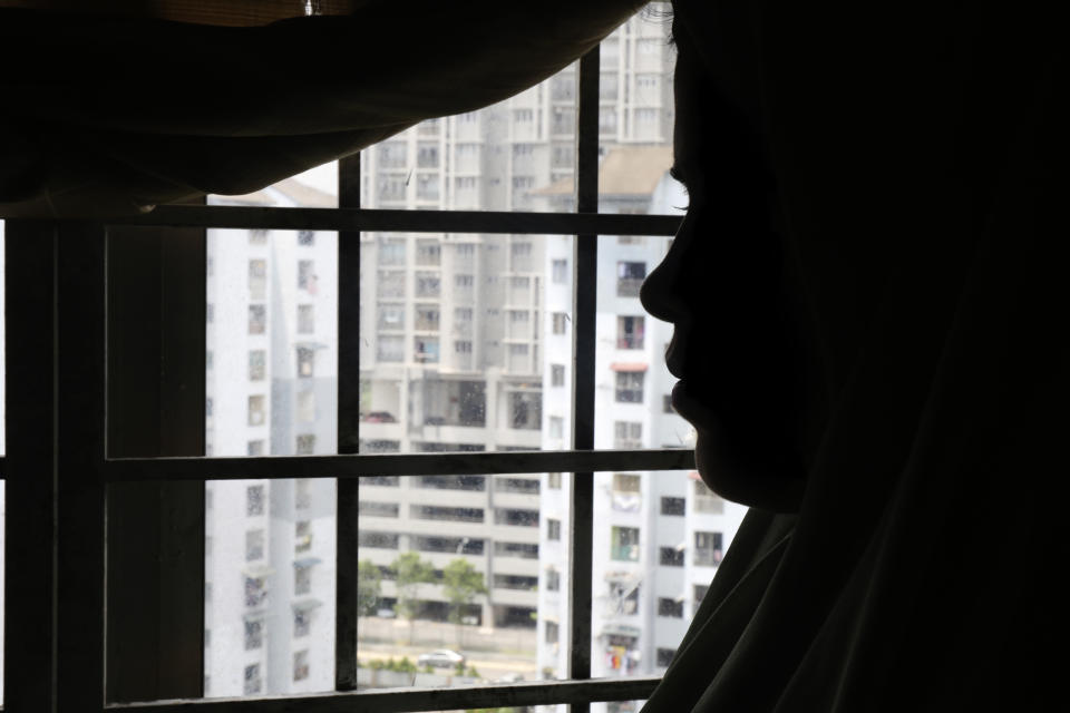 Rohingya child bride, N, age 16, stands next to a window in an apartment in Kuala Lumpur, Malaysia, on Oct. 4, 2023. An older man in Malaysia helped pay a trafficker for her passage to Malaysia in 2023 so that she could marry him. (AP Photo/Victoria Milko)