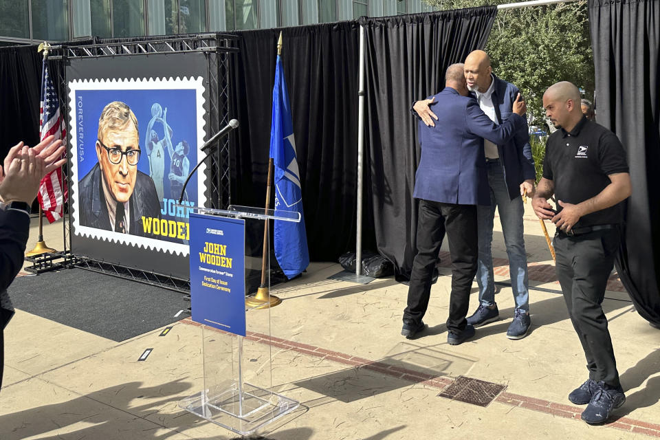 Jamaal Wilkes, left, hugs Kareem Abdul-Jabbar at the first-day-of-issue for the John Wooden forever stamp ceremony on the UCLA campus in Los Angeles, California, Saturday, Feb. 24, 2024. Wilkes and Abdul-Jabbar played on some of Wooden’s record 10 national championship basketball teams in the 1960s and 1970s. Wooden died in 2010 at age 99. (AP Photo/Beth Harris)