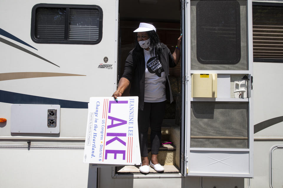 In this Friday, June 19, 2020, photo Jeannine Lee Lake, Democratic candidate for Indiana's 6th congressional district, passes out yard signs from her motorhome during a Juneteenth day event in Columbus, Ind. Lake never would have imagined when she first ran against Greg Pence, Vice President Mike Pence’s brother, for a rural Indiana congressional seat two years ago: An almost entirely white crowd of more than 100 people marching silently in the Pences' hometown, sending up prayers for Black people killed by police and an end to systemic racism. (AP Photo/Michael Conroy)