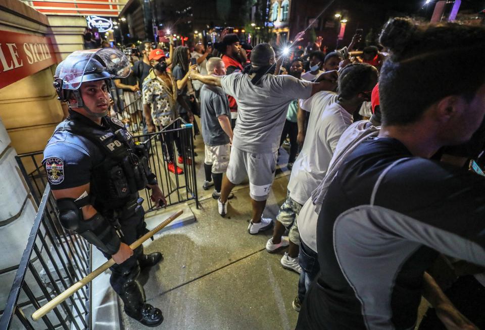 Protesters surround Louisville Metro Police Department officer Galen Hinshaw in front of Bearno's restaurant on Thursday, May 28, 2020 in Louisville, Kentucky.  Five strangers, including Julian De La Cruz, Ricky McClellan and Darrin Lee Jr., linked arms to keep the crowd from getting to Hinshaw.