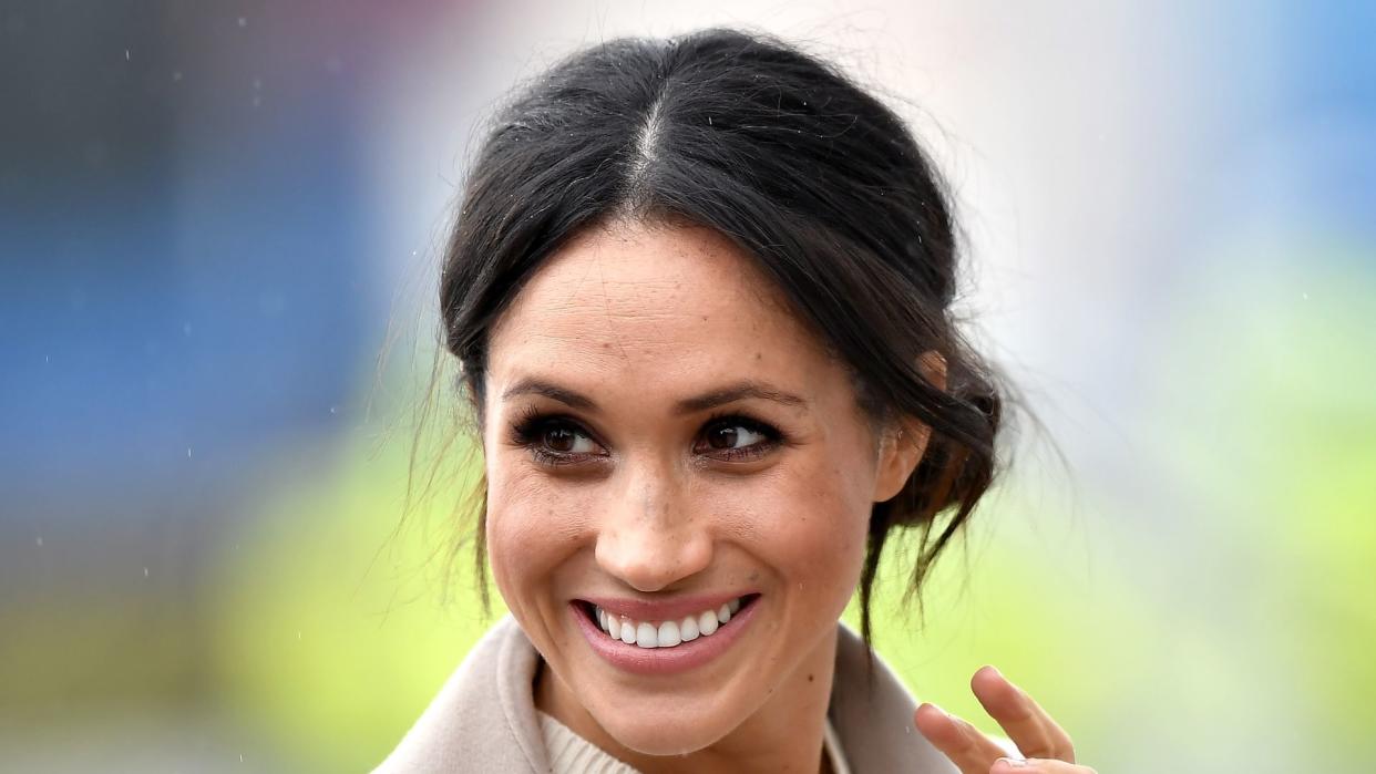 woman waving in cream jumper