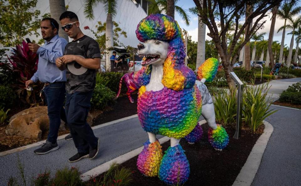 Dos hombres caminan junto a la estatua de un caniche en los jardines escultóricos del Dogs and Cats Walkway. La ciudad de Miami organizó una ceremonia de corte de cinta para la inauguración del paseo y jardín el pasado viernes 10 de febrero.