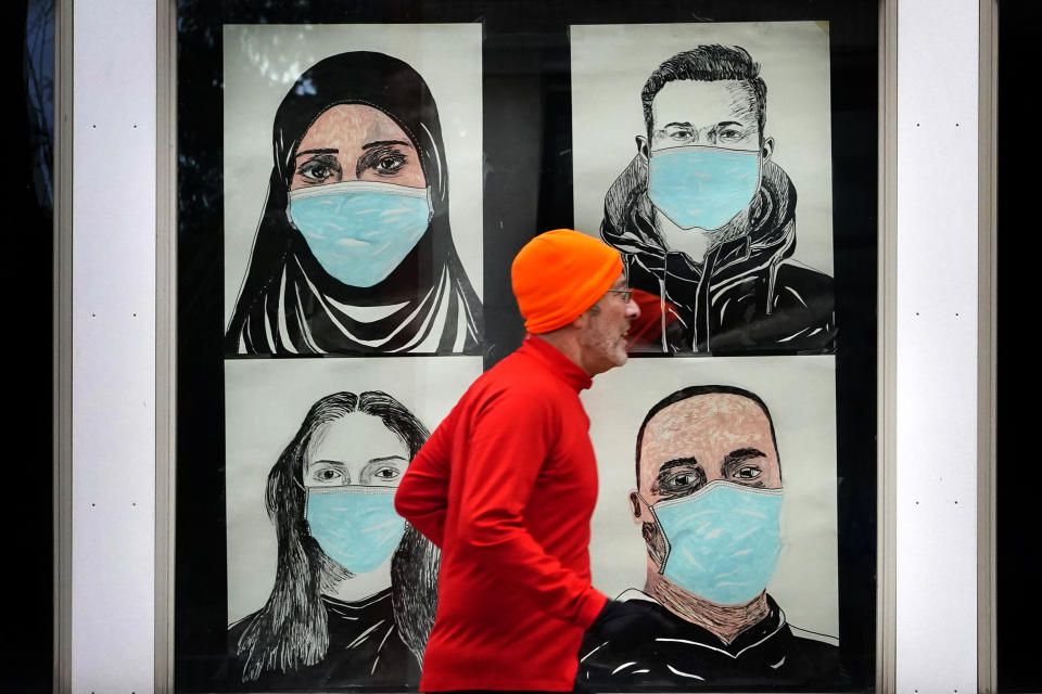 FILE - In this Nov. 16, 2020, file photo, a runner passes by a window displaying portraits of people wearing face coverings to help prevent the spread of the coronavirus in Lewiston, Maine. A deadly rise in COVID-19 infections is forcing state and local officials to adjust their blueprints for fighting a virus that is threatening to overwhelm health care systems. Schools are scrapping plans to reopen classrooms. More states are adopting mask mandates. (AP Photo/Robert F. Bukaty, File)