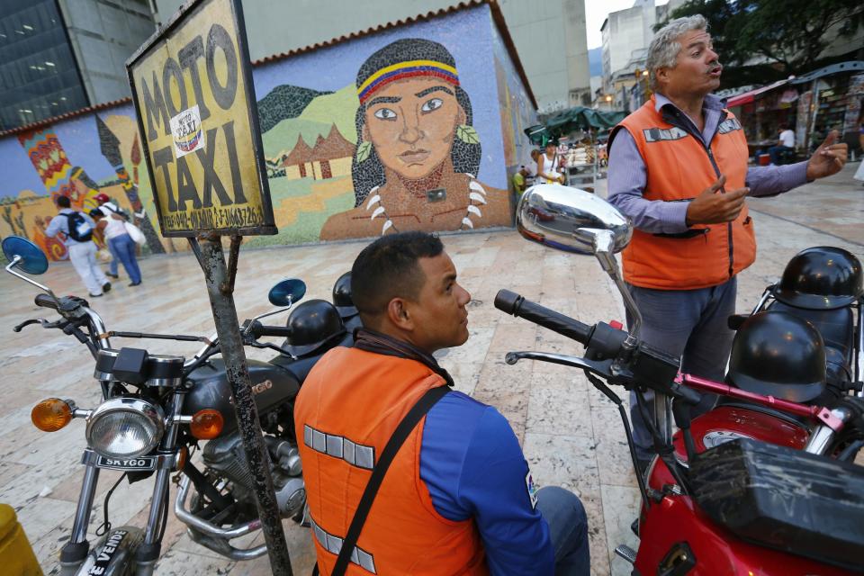 Motorcycle taxi drivers wait for customers in downtown Caracas