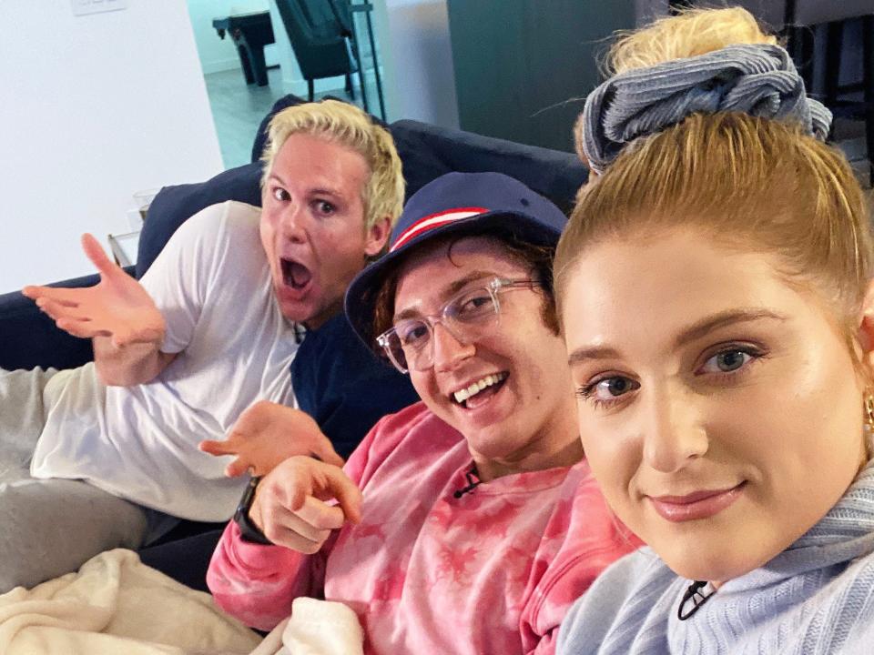 meghan trainor talking a selfie of her, daryl sabara, and her brother ryan trainor, sitting together on their couch