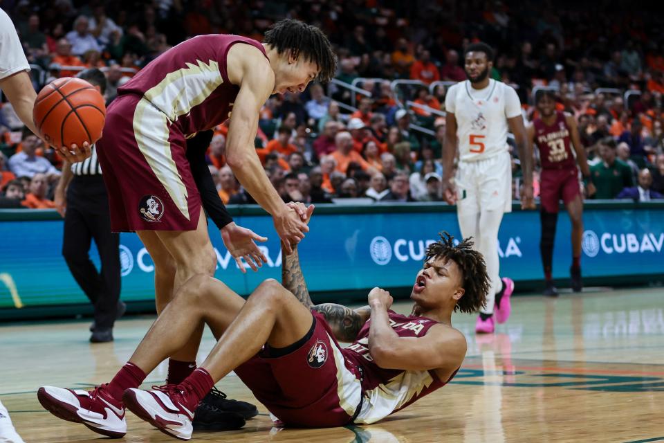Jan 17, 2024; Coral Gables, Florida, USA; Florida State Seminoles forward Cam Corhen (3) reacts as he gets help getting up from guard Jalen Warley (1) during the first half at Watsco Center. Mandatory Credit: Sam Navarro-USA TODAY Sports
