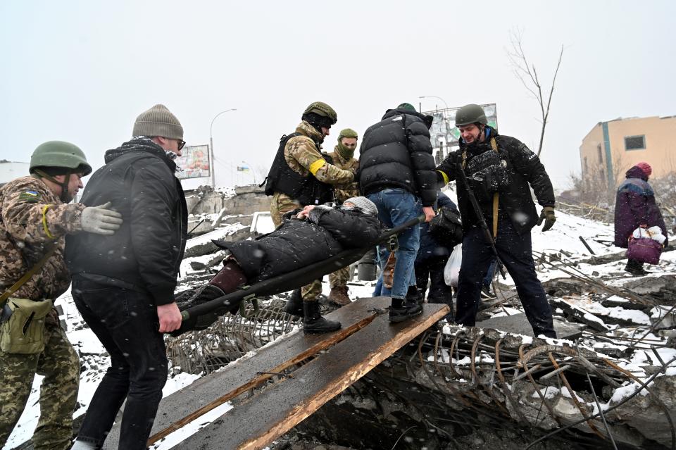 People carry a wounded woman on a stretcher during the evacuation of civilians in Irpin. 