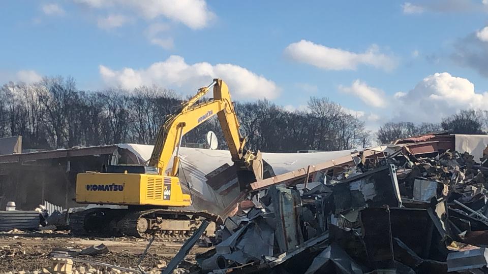 An excavator on Thursday knocks down a roof covering a section of the former Carnation City Mall in Alliance.