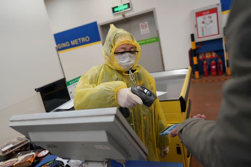 Worker scans a customer's mobile phone for payment at a checkout counter inside a supermarket, as the country is hit by an outbreak of the novel coronavirus, in Beijing