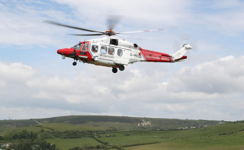 An AgustaWestland AW189 helicopter from HM Coastguard comes in to land on the cliff side near to Overcombe in Dorset, during a training exercise.