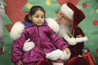 Santa Claus poses with a child at the Trapper School in Nuiqsut, Alaska, on Tuesday, Nov. 29, 2002. Operation Santa Claus, the Alaska National Guard's outreach program, attempts to bring Santa and Mrs. Claus and gifts to children in two or three Alaska Native villages each year, including Nuiqsut in 2022. (AP Photo/Mark Thiessen)