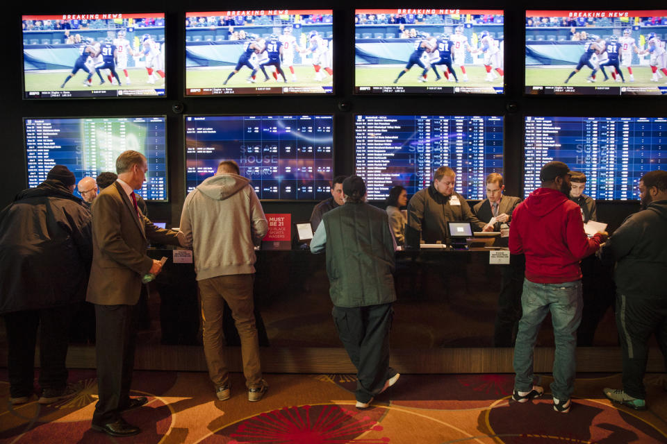 FILE - In this Thursday, Dec. 13, 2018, file photo, gamblers place bets in the temporary sports betting area at the SugarHouse Casino in Philadelphia. About six in 10 Americans want betting on professional sports events to be legal in their state, but fewer feel that way about college athletics, according to a new poll conducted by The Associated Press-NORC Center for Public Affairs Research released Wednesday, March 20, 2019. The poll finds 42 percent favor legal betting on college sports. (AP Photo/Matt Rourke, File)