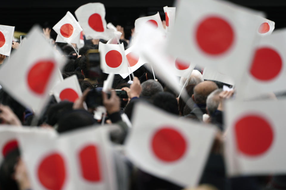 Well-wishers wave Japanese flags while waiting to see Japan's Emperor Naruhito making New Year's public appearance with his imperial families at Imperial Palace in Tokyo Thursday, Jan. 2, 2020. (AP Photo/Eugene Hoshiko)