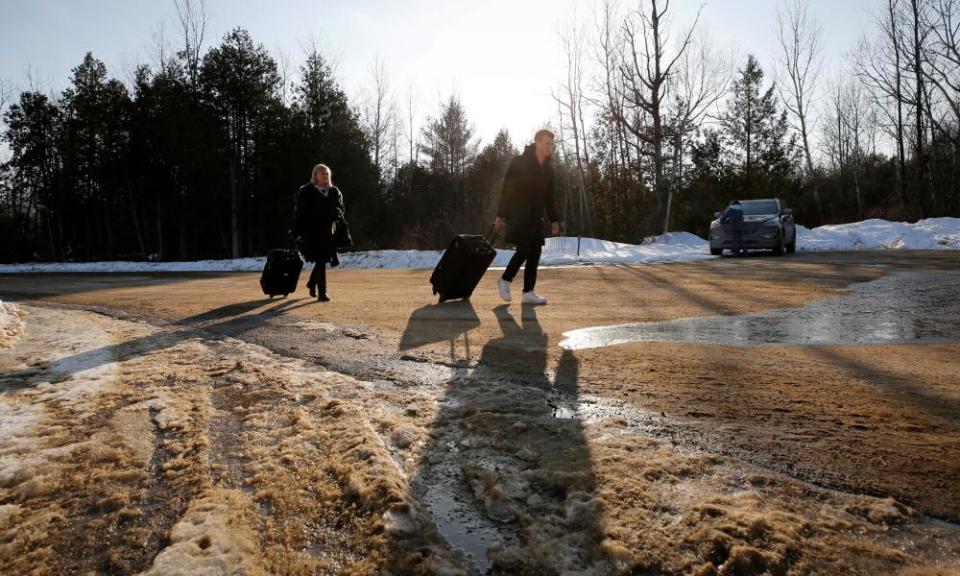 People walk with their luggage on Roxham Road before crossing the US-Canada border.