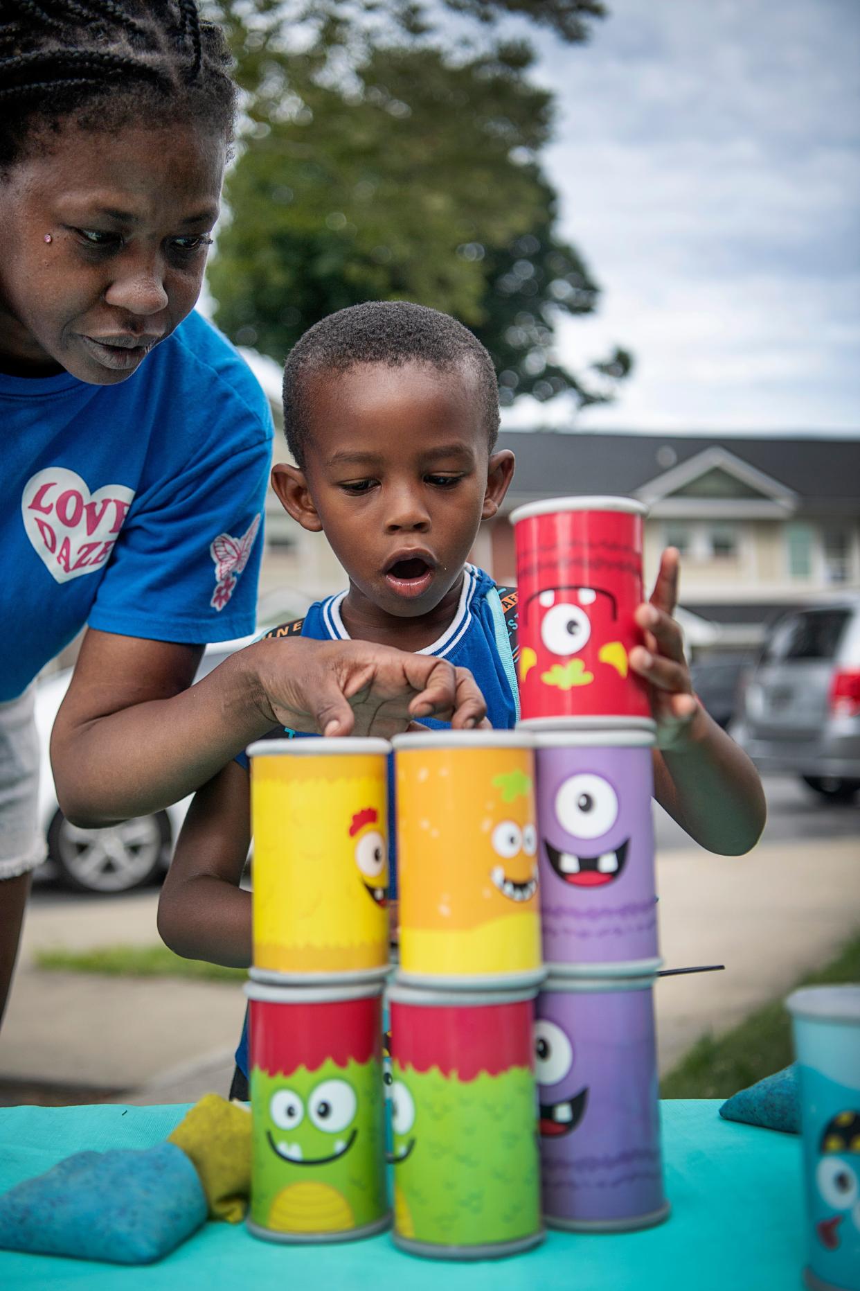 I’za Resper, 5, stacks cans to knock them down with his mother, Leticia, at Head Start’s open house July 19, 2023 in Asheville.