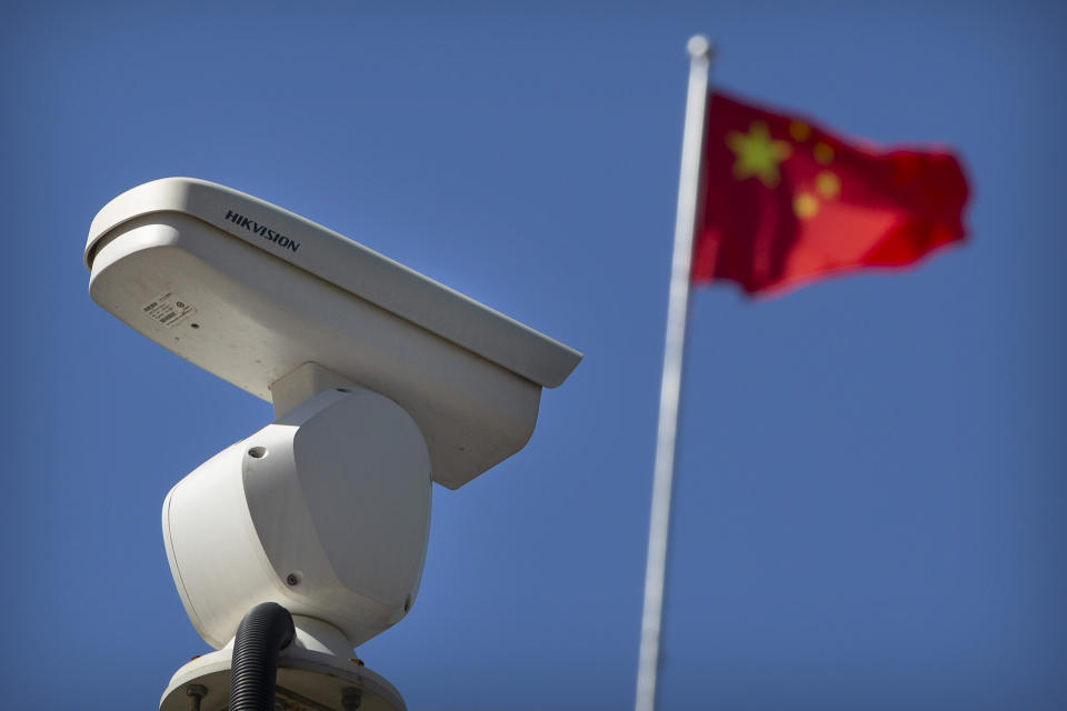 A Chinese flag flies near a Hikvision security camera monitoring a traffic intersection in Beijing, Tuesday, Oct. 8, 2019. The United States is blacklisting a group of Chinese tech companies that develop facial recognition and other artificial intelligence technology that the U.S. says is being used to repress China's Muslim minority groups. (AP Photo/Mark Schiefelbein)