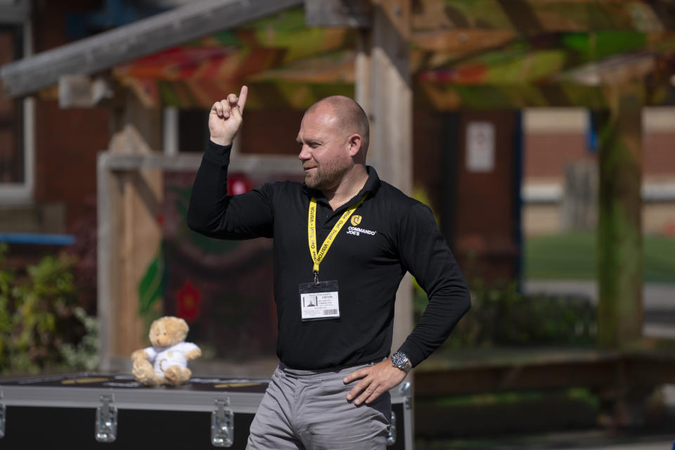 Former soldier Mike Hamilton gestures as he interacts with children at Seymour Road Academy during a Commando Joe's character education program in Manchester, England, Wednesday May 20, 2020. (AP Photo/Jon Super)