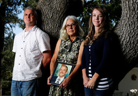 Nancy Schrock holds a picture of her late husband Thomas as she poses for a photograph between her son Matthew and daughter Sarah while at her home in Oak Glen, California July 26, 2016. REUTERS/Mike Blake/Files