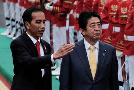Indonesian President Joko Widodo (L) and Japanese Prime Minister Shinzo Abe inspect the honour guards during a welcoming ceremony at the Bogor Palace, West Java, Indonesia January 15, 2017. REUTERS/Beawiharta