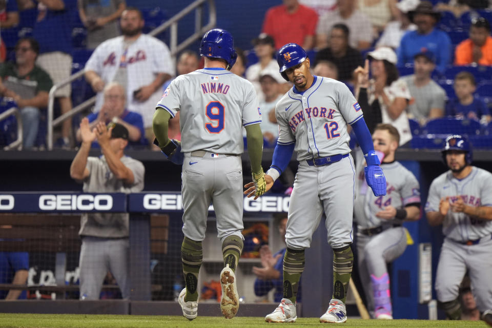New York Mets' Brandon Nimmo (9) and Francisco Lindor (12) congratulate each other after they scored on a double by Tyrone Taylor, during the first inning of a baseball game against the Miami Marlins Sunday, May 19, 2024, in Miami. (AP Photo/Wilfredo Lee)