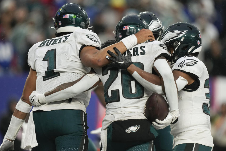 Philadelphia Eagles running back Miles Sanders (26) celebrates with quarterback Jalen Hurts (1) and teammates after scoring a touchdown against the New York Giants during the fourth quarter of an NFL football game, Sunday, Dec. 11, 2022, in East Rutherford, N.J. (AP Photo/Bryan Woolston)