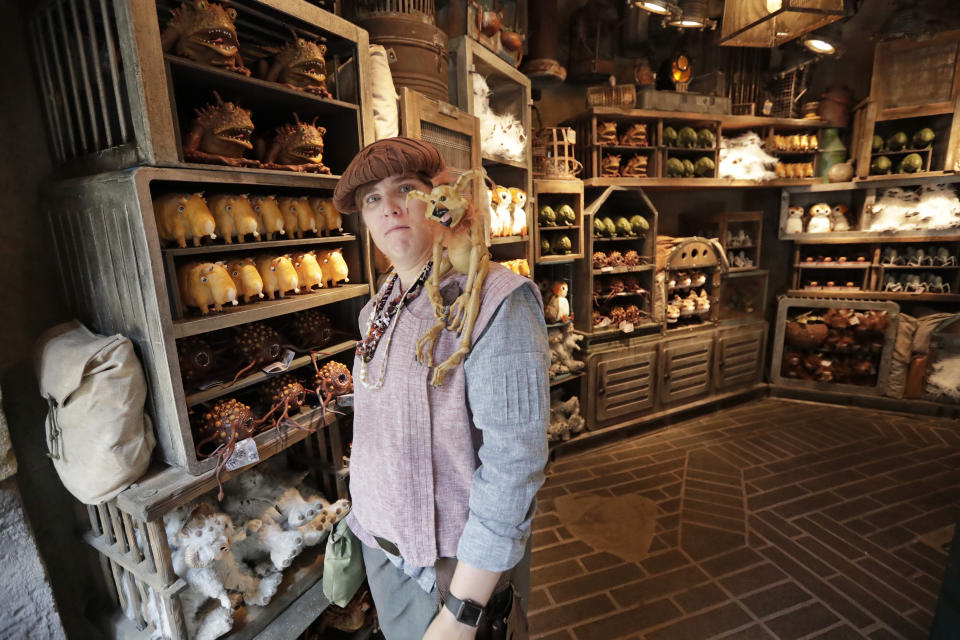 A shop keeper displays creatures that will sit on your shoulder and other merchandise for sale during a preview of the Star Wars themed land, Galaxy's Edge in Hollywood Studios at Disney World, Tuesday, Aug. 27, 2019, in Lake Buena Vista, Fla. The attraction will open Thursday to park guests. (AP Photo/John Raoux)