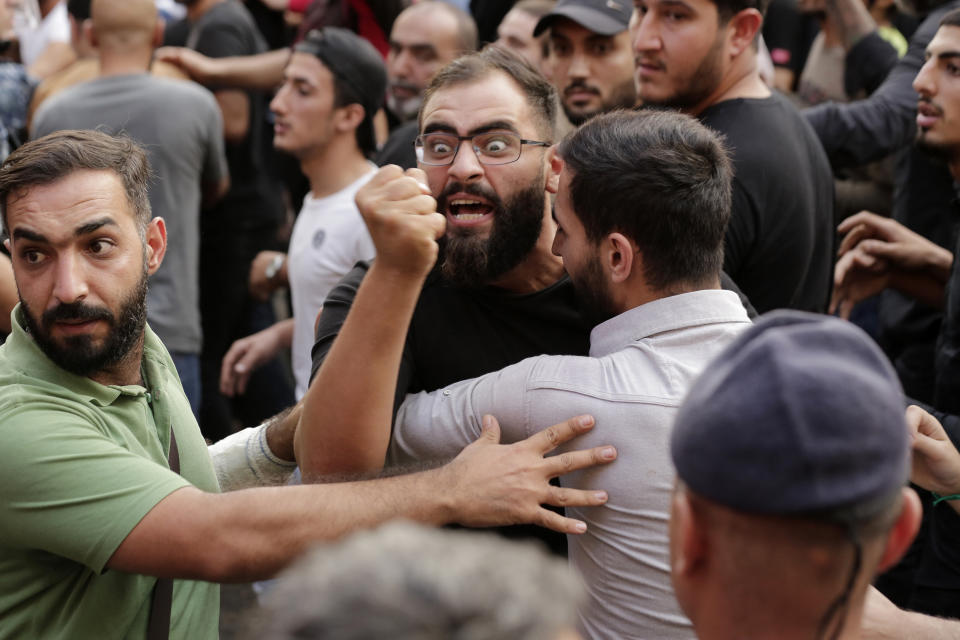 Anti-government protesters and Hezbollah supporters clash during a protest in Beirut, Lebanon, Friday, Oct. 25, 2019. Leader of Lebanon's Hezbollah calls on his supporters to leave the protests to avoid friction and seek dialogue instead. (AP Photo/Hassan Ammar)