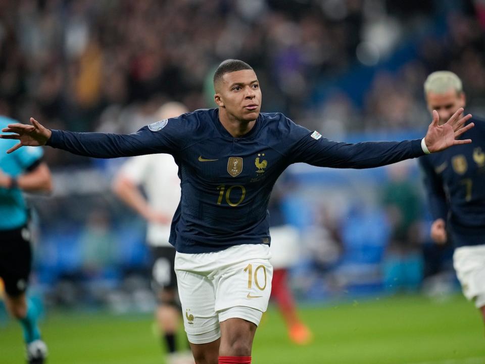 Kylian Mbappe runs with his arms out in celebration during a France soccer match.