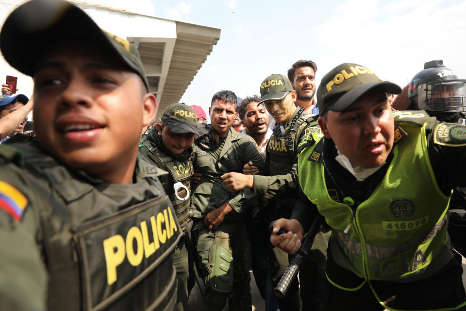 FILE - In this Feb. 23, 2019 file photo, Colombian police escort a Venezuelan soldier who defected,at the Simon Bolivar international bridge, where Venezuelans tried to deliver humanitarian aid despite objections from President Nicolas Maduro, in Cucuta, Colombia. About 1,000 members of the Venezuelan security forces have fled to Colombia since February, giving up weapons and uniforms as they abandon Maduro's government, said Colmbian authorities on March 18. (AP Photo/Fernando Vergara, File)