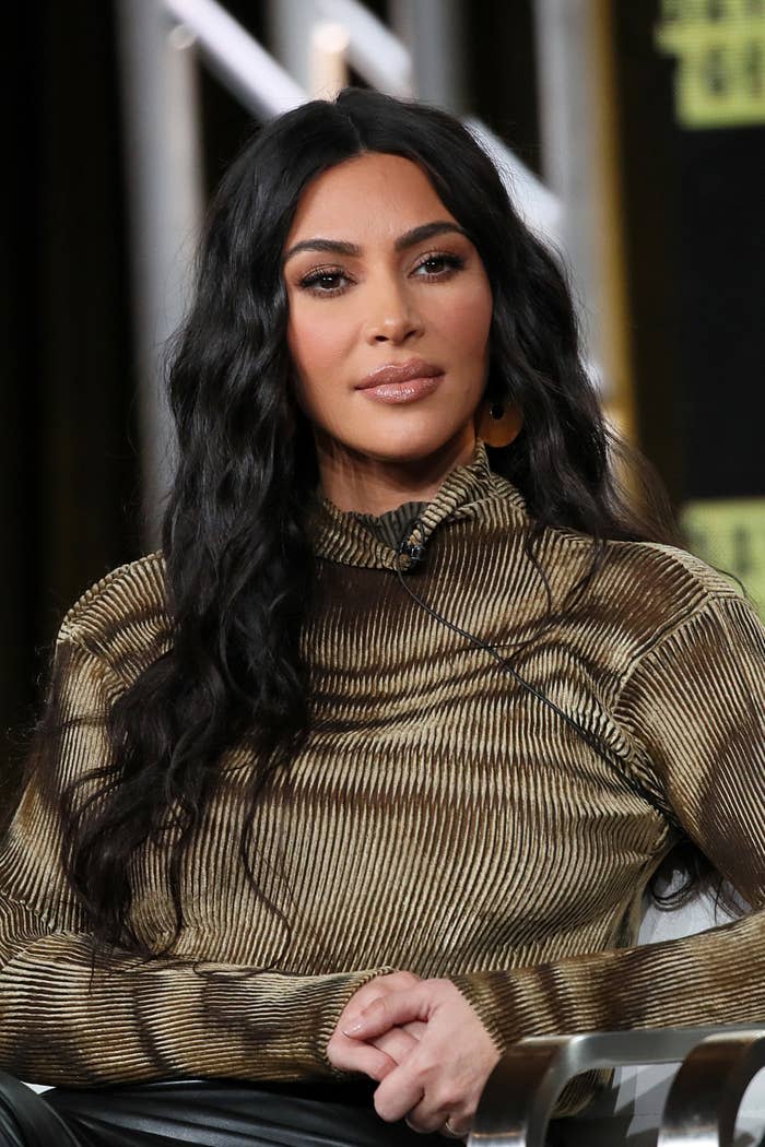 Kim with her hands clasped as she sits on a stage