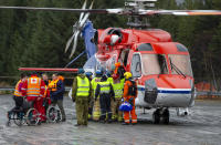 Passengers are helped from a rescue helicopter in Fraena, Norway, Sunday March 24, 2019, after being rescued from the Viking Sky cruise ship. Rescue workers are evacuating more passengers from a cruise ship that had engine problems in bad weather off Norway's western coast while authorities prepare to tow the vessel to a nearby port. (Svein Ove Ekornesvag/NTB Scanpix via AP)