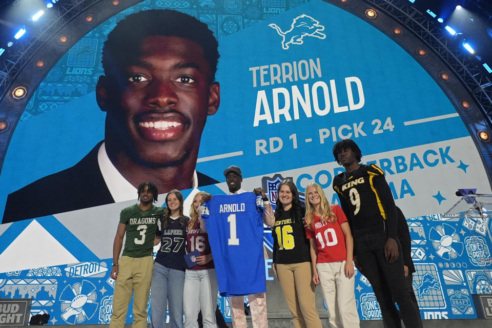 Alabama cornerback Terrion Arnold, center, poses after being chosen by the Detroit Lions with the 24th overall pick during the first round of the NFL football draft, Thursday, April 25, 2024, in Detroit. (AP Photo/Paul Sancya)