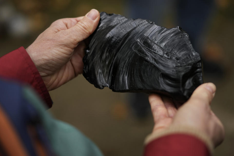 A piece of obsidian, an example of what could be found at the Mound City Group, is passed around a tour group at the Mound City Group at Hopewell Culture National Historical Park in Chillicothe, Ohio, Saturday, Oct. 14, 2023. A network of ancient American Indian ceremonial and burial mounds in Ohio noted for their good condition, distinct style and cultural significance, including Hopewell, was added to the list of UNESCO World Heritage sites. (AP Photo/Carolyn Kaster)