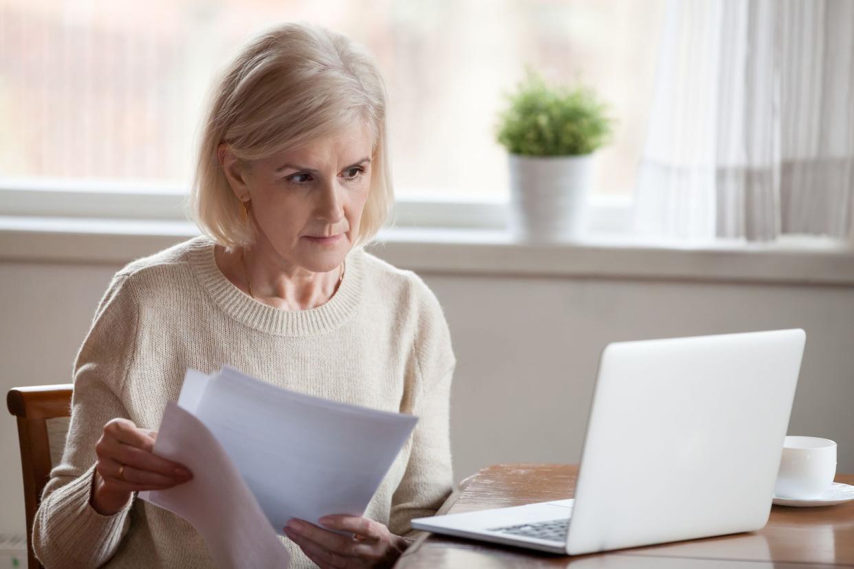 senior woman looking at laptop and papers