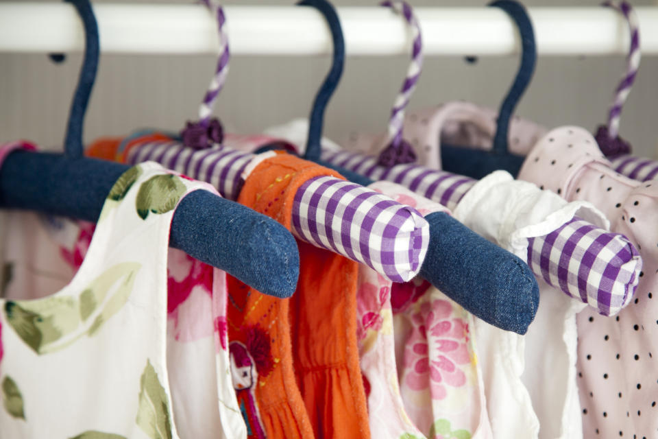 Children's clothes on hangers, with various patterns and a blue sock hanging on one