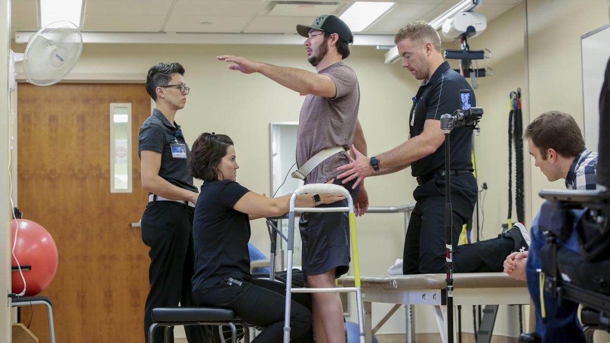 Jered Chinnock (3.v.l) seht mit seinem Therapieteam in der Mayo Clinic. Mittels elektrischer Rückenmarkstimulation und 43 Wochen Rehabilitationstherapie konnte der Patient mit 331 Schritten 102 Meter zurücklegen. Foto: Teresa Crawford/AP