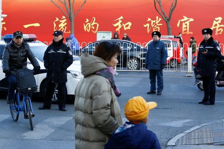 Police watch as a woman and a child leave a primary school that was the scene of an attack in Beijing, China, January 8, 2019. REUTERS/Thomas Peter