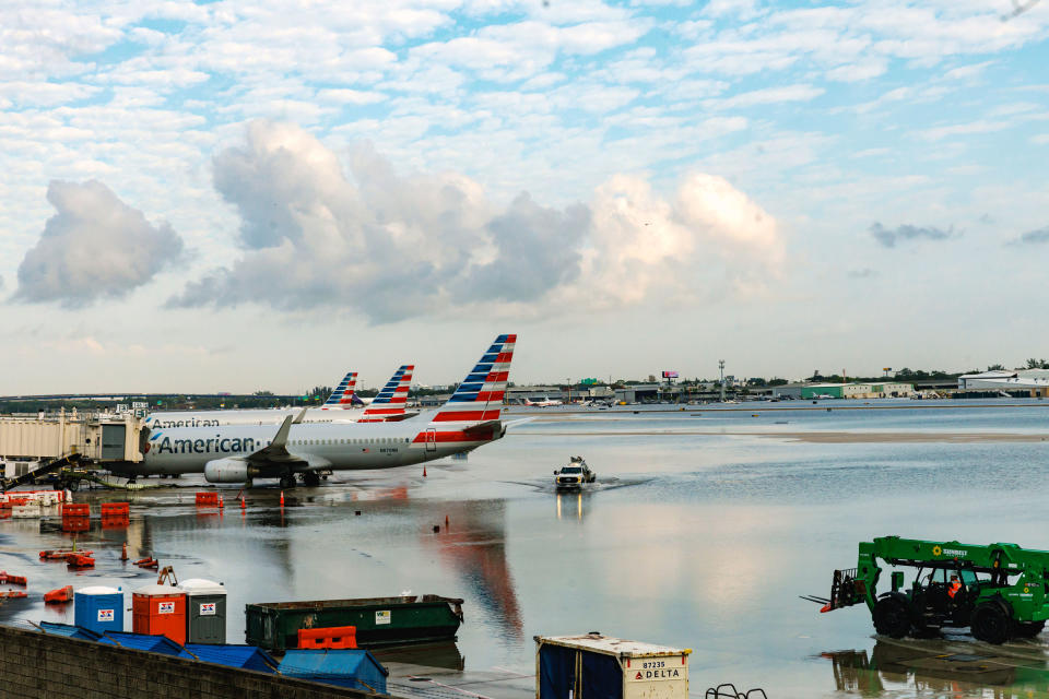 American Airlines airplanes sit at the terminal as a truck drives through the flooded tarmac at the Fort Lauderdale-Hollywood International Airport on April 13, 2023.<span class="copyright">David Santiago—Miami Herald/AP</span>