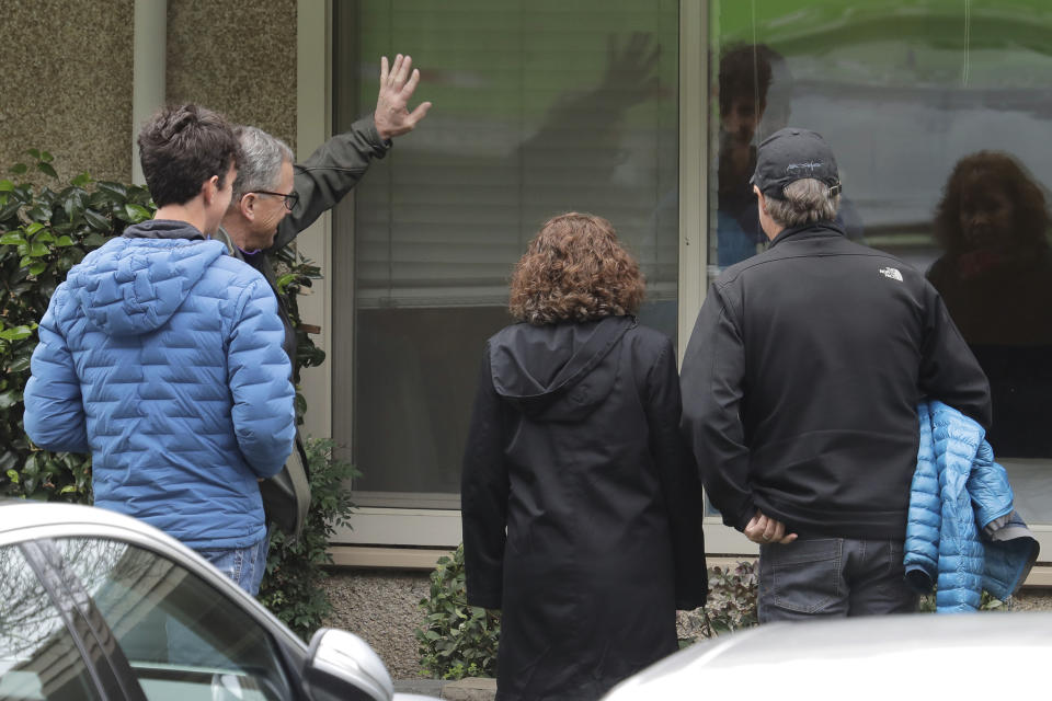 In this March 12, 2020, photo, family members of Chuck Sedlacek wave and greet him through reflections in the window of his room at Life Care Center in Kirkland, Wash., near Seattle. The facility has been at the center of the COVID-19 coronavirus outbreak in the state, and Sedlacek's son Scott said that he and his siblings have barely spoken to their father inside the center, who in addition to testing positive for the coronavirus, has blindness, neuropathy, and has difficulty using a phone, saying he is more of an "inmate" than a patient. Residents of assisted living facilities and their loved ones are facing a grim situation as the coronavirus spreads across the country, placing elderly people especially at risk. (AP Photo/Ted S. Warren)