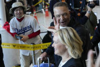 A supporter, left, wears a Los Angeles Dodgers jersey as manager Dave Roberts, top, gestures while walking with his wife, Tricia Roberts, during the baseball team's arrival at Incheon International Airport, Friday, March 15, 2024, in Incheon, South Korea, ahead of the team's baseball series against the San Diego Padres. (AP Photo/Ahn Young-joon)