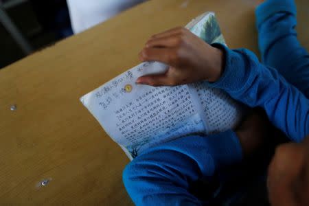 A child holds a book during a Chinese language lesson in a school at Namtit, Wa territory in northeast Myanmar November 30, 2016. REUTERS/Soe Zeya Tun