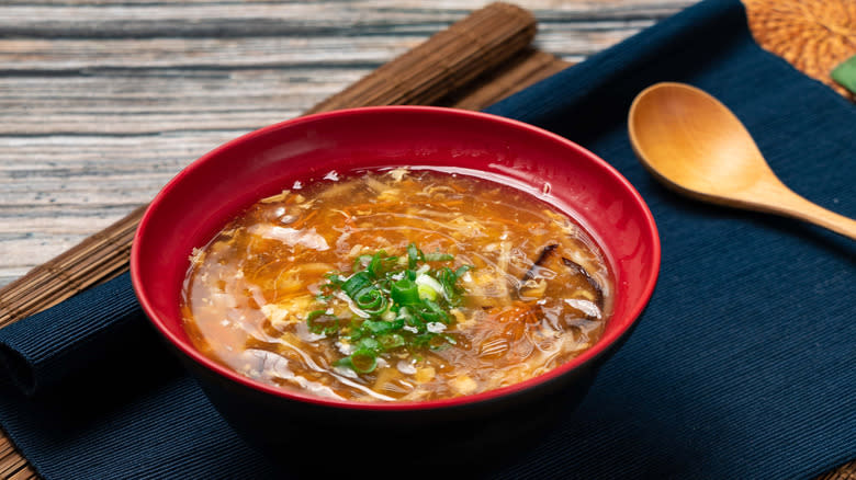 Hot and sour soup in red bowl with wooden spoon