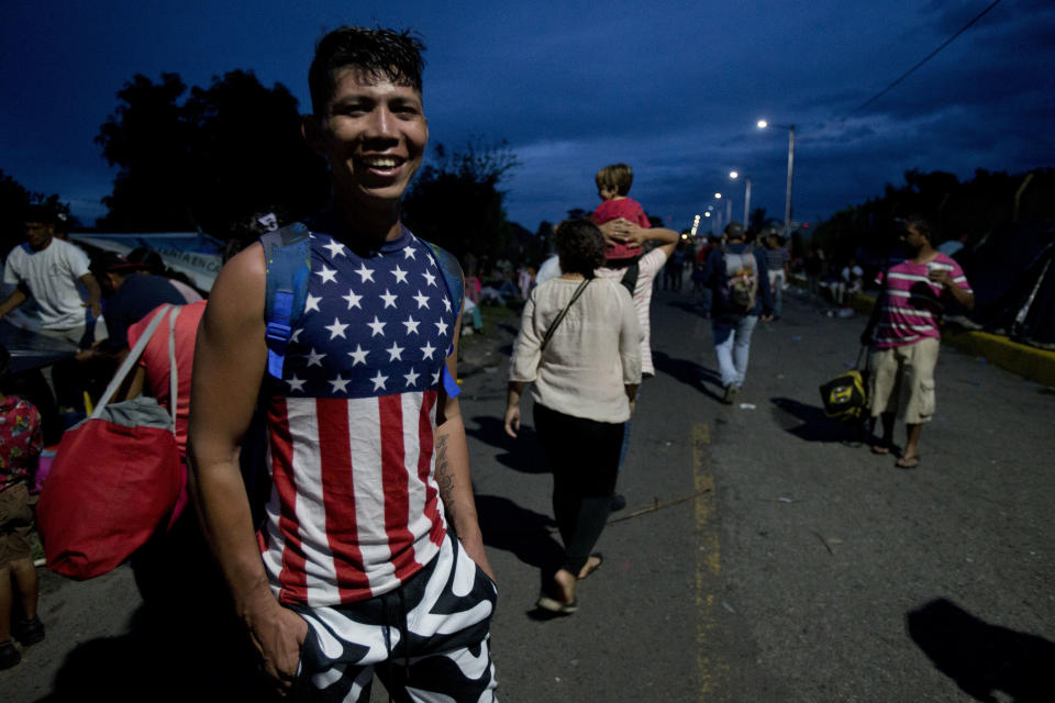 Honduran migrant Carlos Deras, 26, smiles as he poses for a portrait at the border between Guatemala and Mexico, in Tecun Uman, Guatemala, as the sun sets Saturday, Oct. 20, 2018, as he travels with a caravan to the U.S. Deras said he joined the caravan with neighbors after he heard about it on social media, and is using his savings to finance his trip. (AP Photo/Moises Castillo)