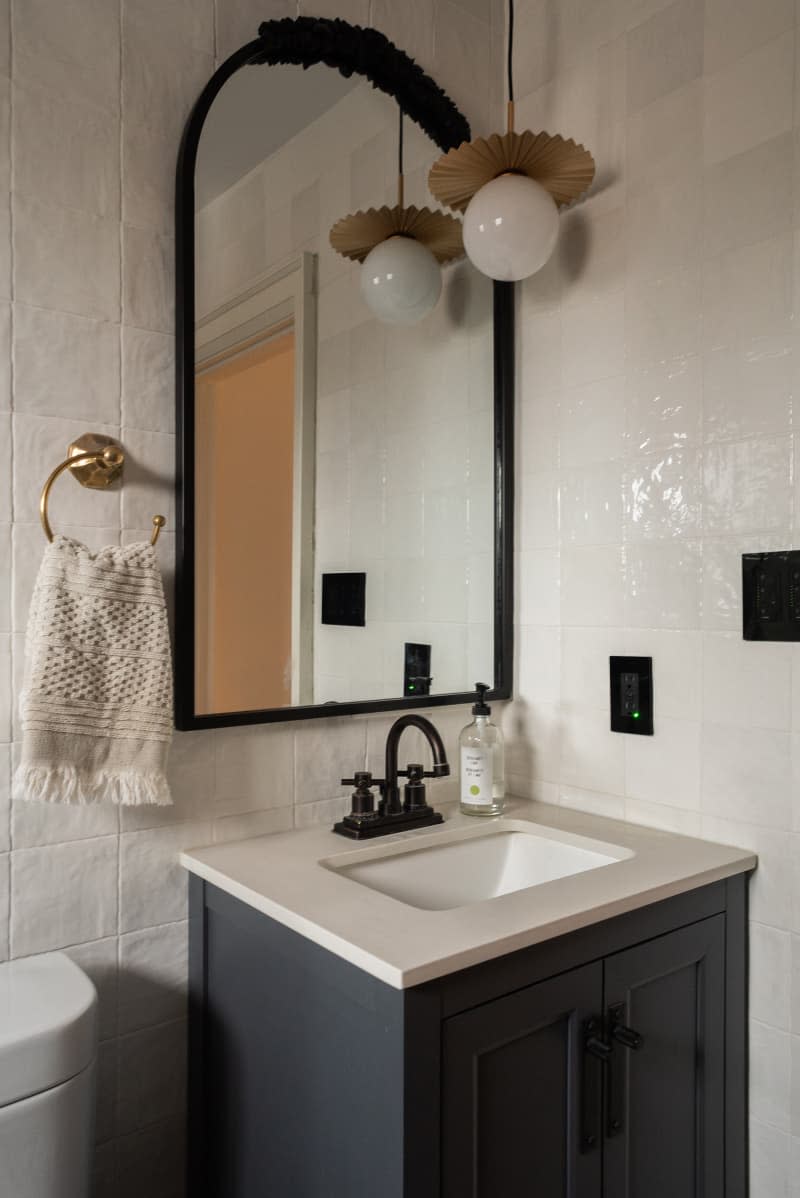 White bathroom with a large black mirror with white countertop.