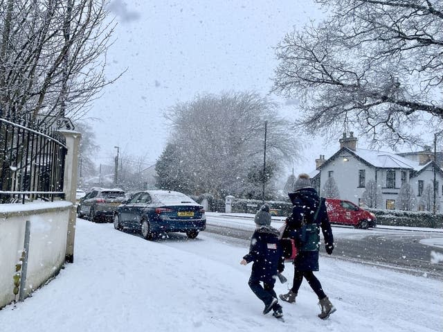 A woman and a child walk through falling snow in Eglinton, Co Londonderry, Northern Ireland 