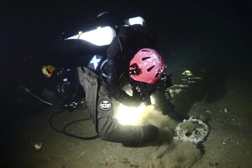 Discovery team member Joe Mazraani fans away the sand to reveal a deadeye used as part of the sail rigging on the passenger steamship Le Lyonnais, during a dive on the wreck, Saturday, Aug. 24, 2024, off the coast of Massachusetts. (Andrew Donn/Atlantic Wreck Salvage via AP)