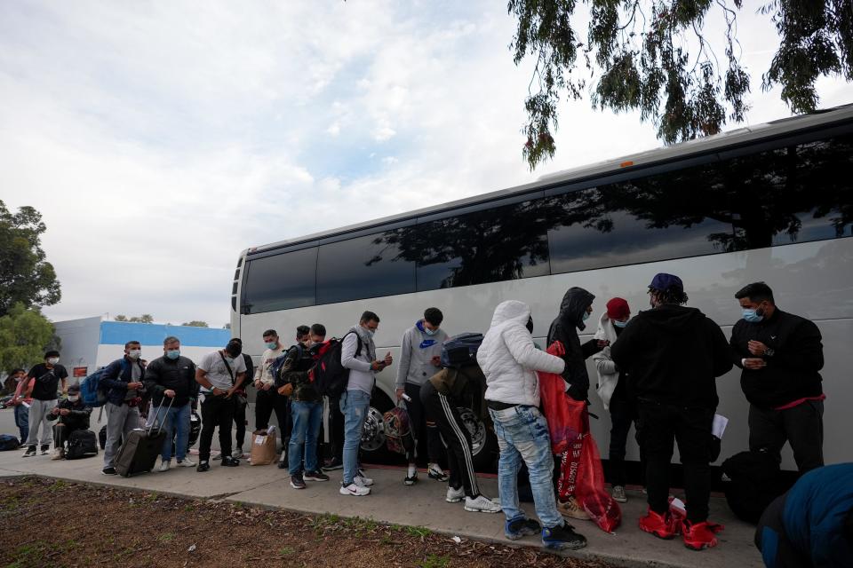 Migrants unload their items off a bus as they arrive at a bus stop after leaving a processing facility, Friday, Feb. 23, 2024, in San Diego. Hundreds of migrants were dropped off at a sidewalk bus stop after local government funding for a reception center ran out of money sooner than expected.