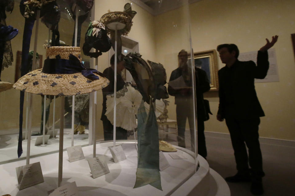 Journalists look on the display of women hats of the 19th century during the press day of the Impressionism and Fashion exhibition in at the Orsay museum in Paris, Friday, Sept. 21, 2012. To coincide with Paris Fashion week, a new and highly original exhibit called "Impressionism and Fashion" opens at the Musee d'Orsay. It uses famous works of art to explore how at the dawn of impressionism, and as an emblem of "modernite" fashion, and how people dressed, became one of the main themes in art. The exhibition will open September 25, 2012 and last till January 2013. (AP Photo/Michel Euler)