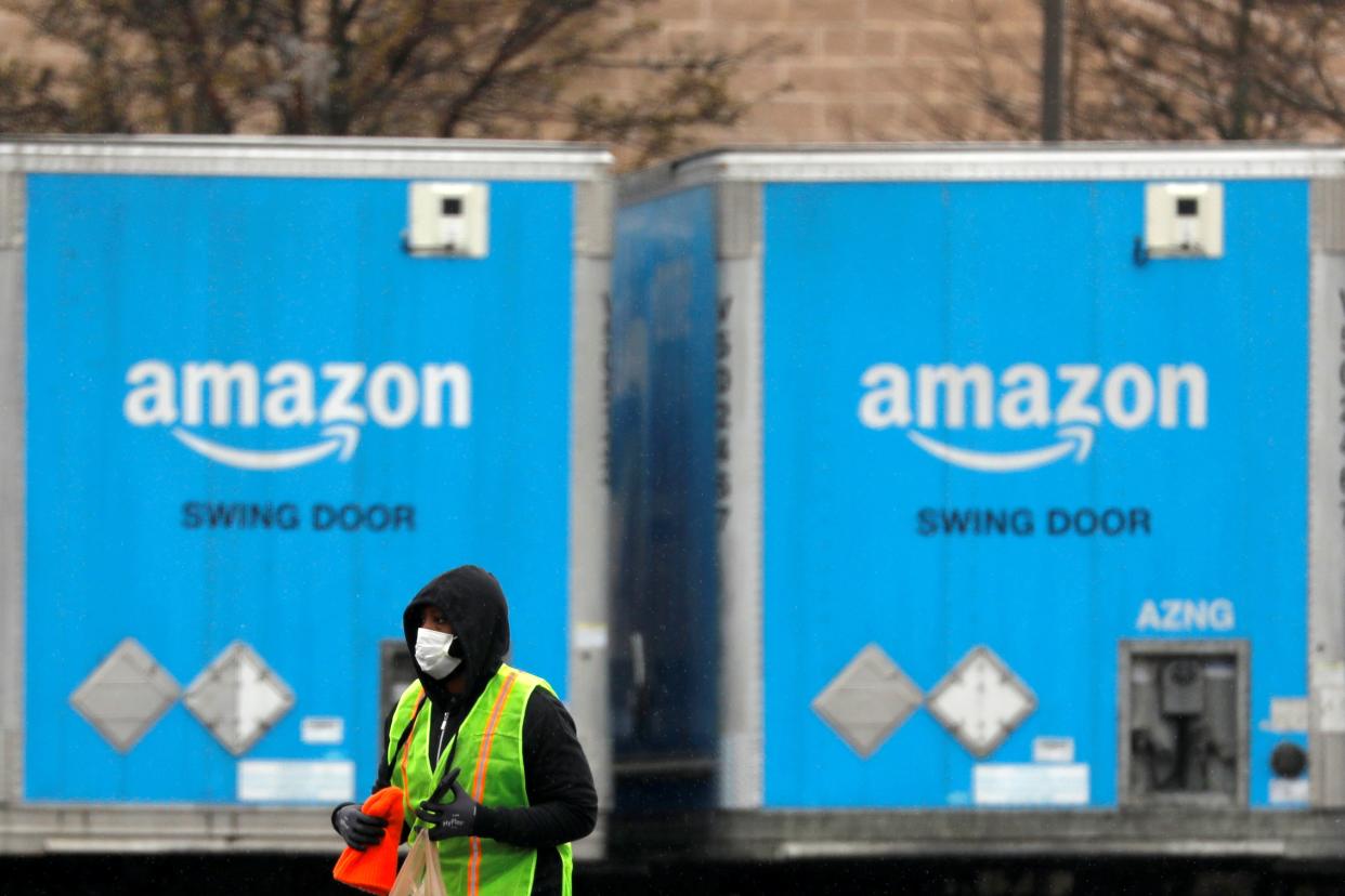 FILE PHOTO: A worker in a face mask walks by trucks parked at an Amazon facility as the global coronavirus outbreak continued in Bethpage on Long Island in New York, U.S., March 17, 2020. REUTERS/Andrew Kelly/File Photo